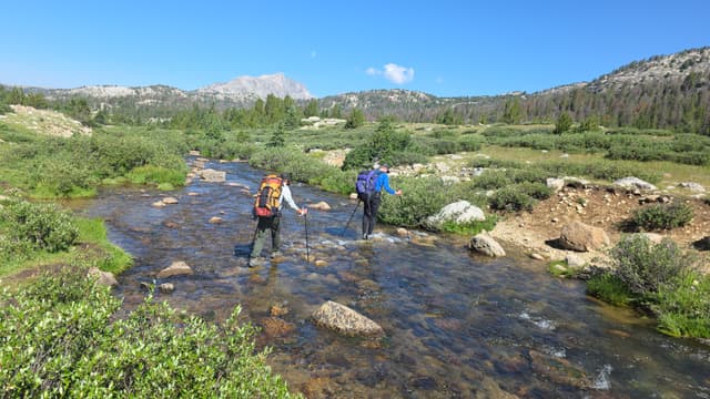 Two hikers crossing a rocky stream