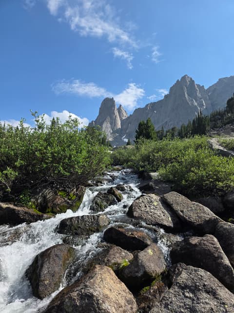 A stream cascading over boulders beneath the towers