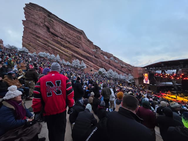 A packed crowd at Red Rocks Amphitheatre with the red rock wall rising behind