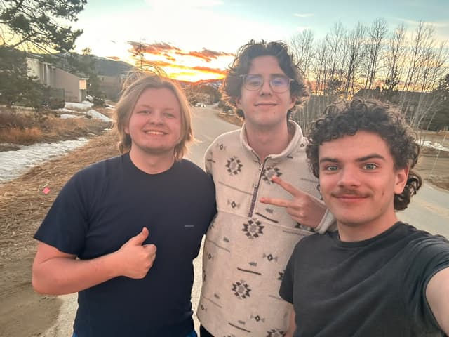Finn and two friends grinning in a selfie at sunset