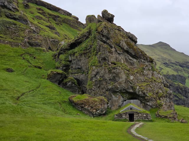 A turf-roofed stone house built into a mossy rock outcrop