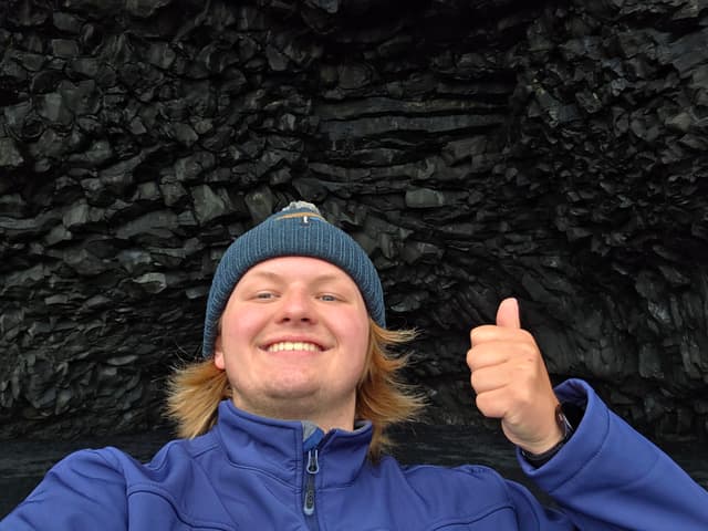 Finn in a beanie in front of the basalt column cave at Reynisfjara