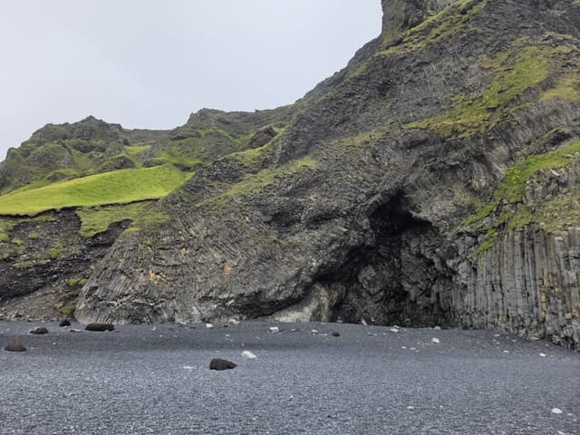 Mossy cliffs and basalt columns above the black sand beach