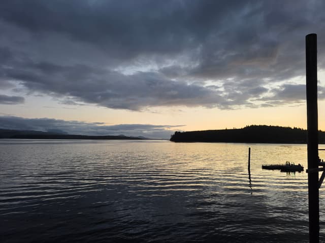 Sunset over calm water beside a dock post