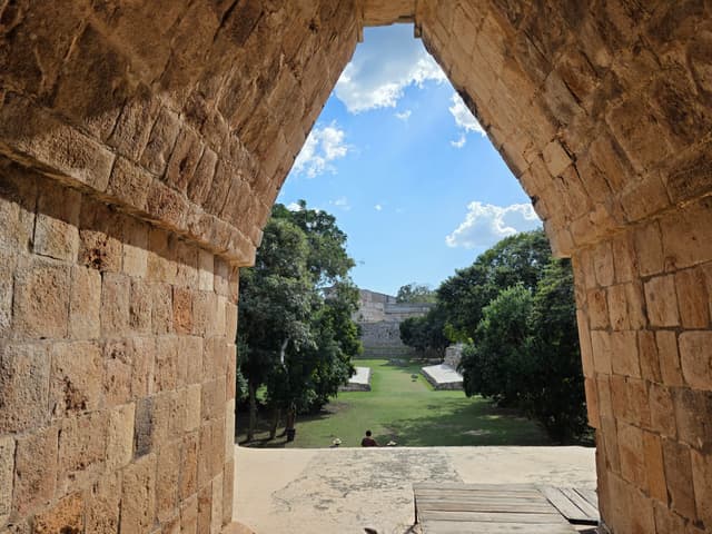 Looking through a stone Maya arch toward the ruins at Uxmal