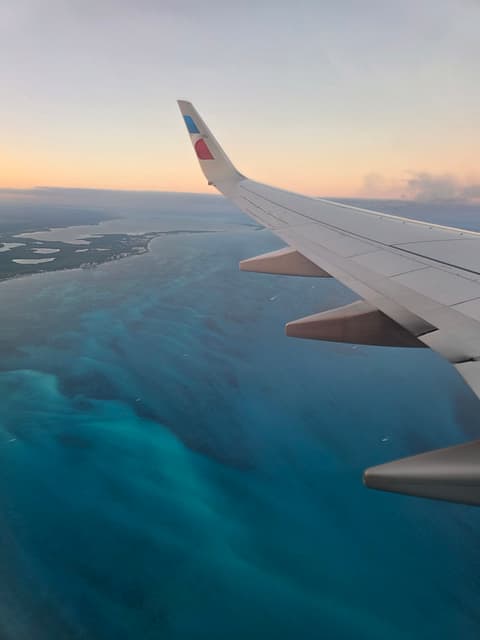 An airplane wing over turquoise Caribbean water